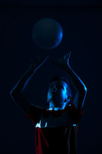 Close-up of boy holding volleyball against black background