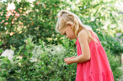 Portrait of young woman standing against plants