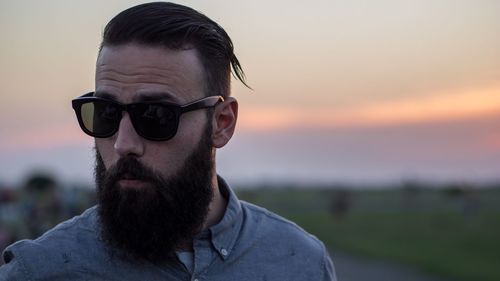 Portrait of man wearing sunglasses against sky during sunset