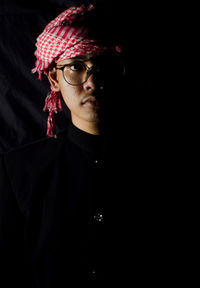 Portrait of teenage boy wearing hat against black background