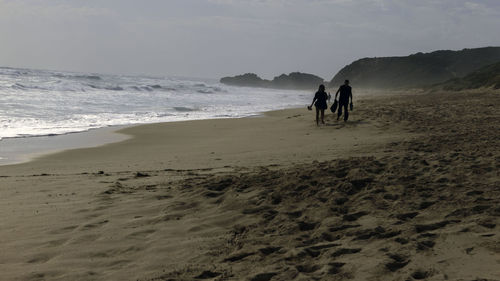People walking on beach against sky
