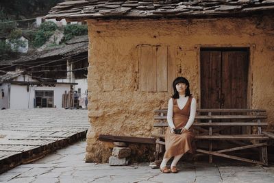 Portrait of woman sitting against building