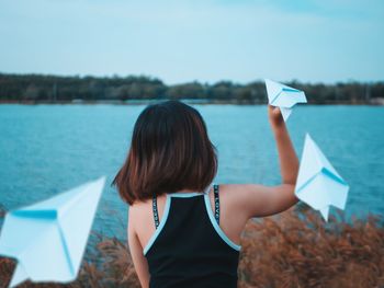 Rear view of woman standing against blue sky