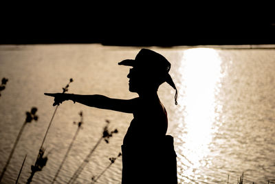 Side view of silhouette woman gesturing against sea during sunset