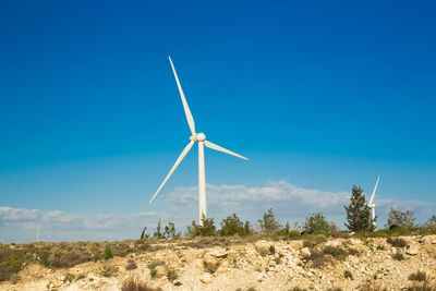 Windmill on field against clear blue sky