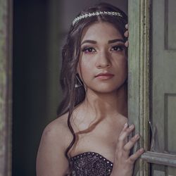 Portrait of beautiful woman wearing tiara while standing behind door