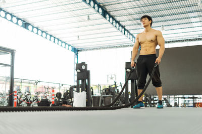 Shirtless male athlete exercising with dumbbells in gym