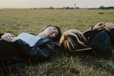 Young female friends lying down on grass in park