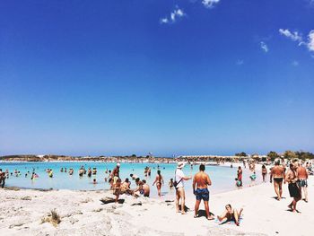 People at elafonissi beach against sky on sunny day