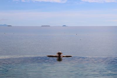 Mature woman swimming in infinity pool against sea