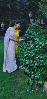 Woman standing by plants in park 