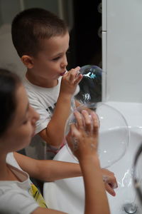 High angle view of siblings blowing bubbles in bathroom at home