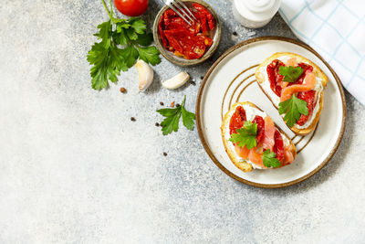 Open sandwiches or bruschetta with salted salmon, cheese and sun dried tomato on a stone table. 