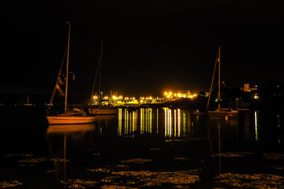 Illuminated boats moored in river at night