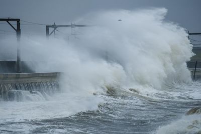 Waves splashing on shore against sky