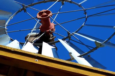 Low angle view of man working against blue sky