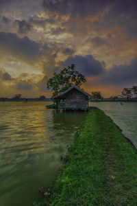 Scenic view of lake by building against sky during sunset