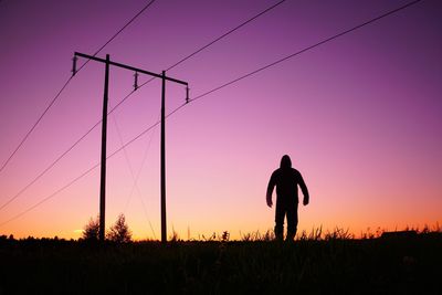 Silhouette man standing on field against sky during sunset