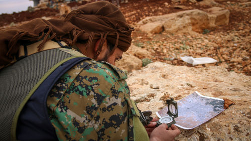 Close-up of man holding compass on land