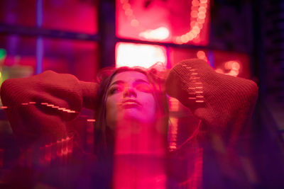 Young woman looking up on red window with blue backlight optical illustration