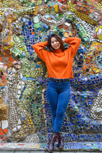 Portrait of a smiling young woman standing against graffiti