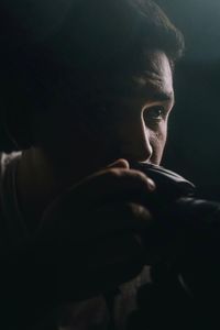 Close-up of young man photographing against black background