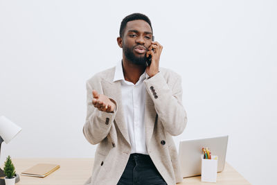 Young man using mobile phone while standing against white background