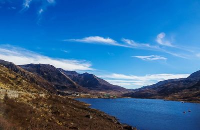 Scenic view of sea and mountains against blue sky