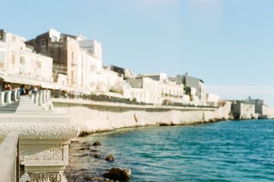Close-up of buildings by sea against clear sky