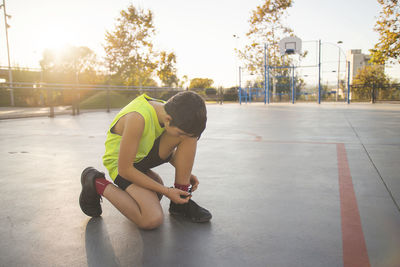 Boy tying shoelace at basketball court