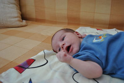 Close-up of baby boy lying on bed at home