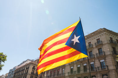 Low angle view of flag against buildings in city against sky