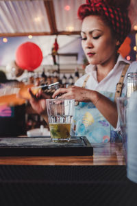 Midsection of woman drinking glass on table at restaurant