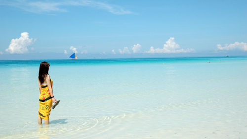 Woman with knee deep in water against sky