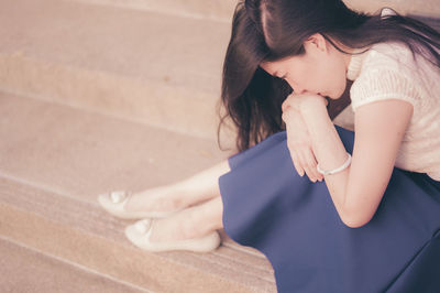 High angle view of woman looking down while sitting outdoors