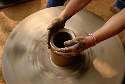 Cropped hands of potter potting pot