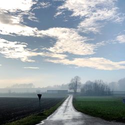 Road amidst field against sky