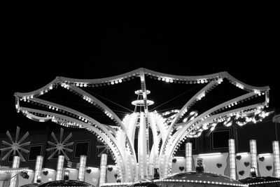 Illuminated carousel against sky at night