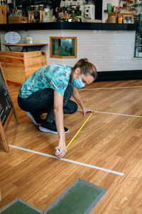 Full length of woman measuring floor