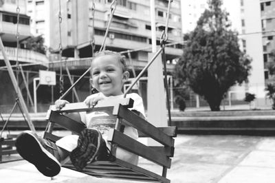 Portrait of happy boy swinging on swing at playground