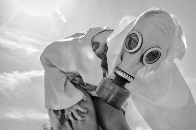 Low angle view of man holding camera against sky