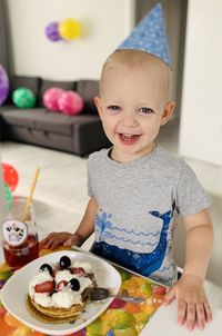 Portrait of cute smiling girl sitting on cake