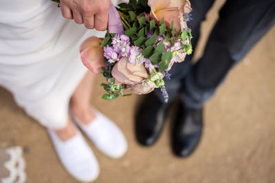 Wedding bouquet on the background of the feet of the bride and groom
