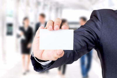 Midsection of man holding business card in office