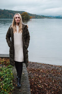 Portrait of young woman standing against lake