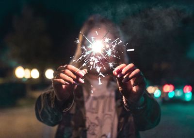 Low angle view of hand holding fireworks at night