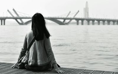 Rear view of woman sitting on shore