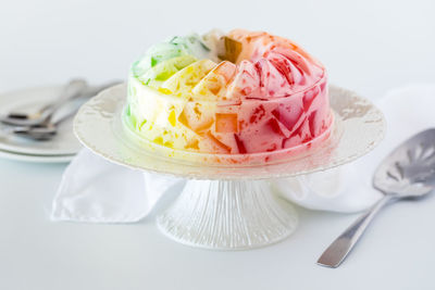 Rainbow fruit flavoured jelly mold on a pedestal stand, ready for serving.