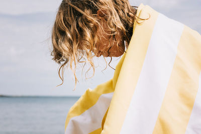 Young girl with curly hair wrapped in a striped towel at the beach