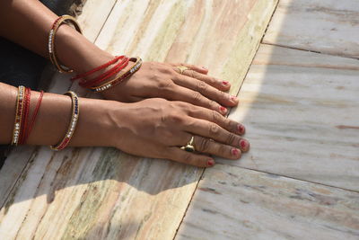 High angle view of woman hands wearing bangles on tiled floor